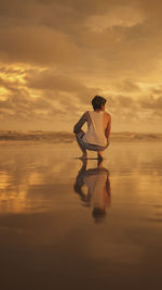 Man standing on beach against sky during sunset