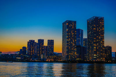 Illuminated modern buildings in city against sky