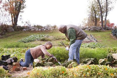 Senior couple gardening in backyard against sky