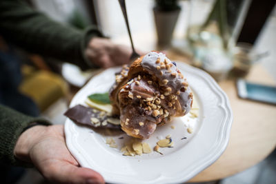 Close-up of hand holding ice cream in plate