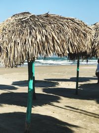 Lounge chairs on sand at beach against sky