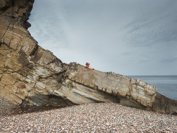 The rocky shore of the sea of japan, on the rocks is a small puffer of a sunbathing man. 