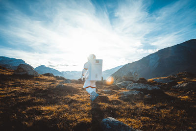 Rear view of man standing on rock against sky