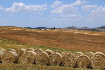 Hay bales on field against sky