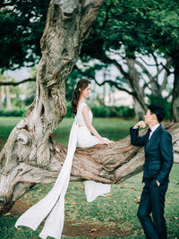 Side view of woman standing on tree trunk