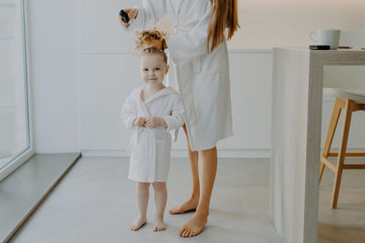 Mother combing daughters hair at home