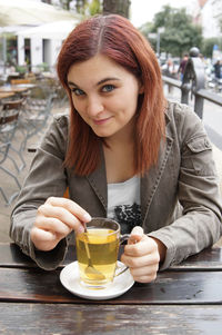 Young woman having drink while sitting at outdoor cafe