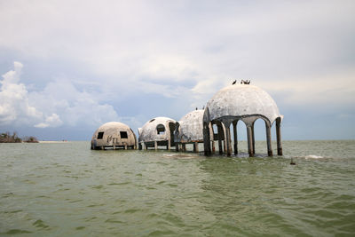 Built structure by sea against sky