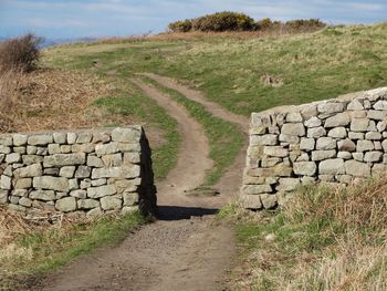 Footpath amidst stone walls leading towards field