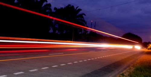 Light trails on road against sky at night