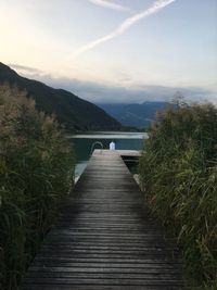 Boardwalk leading towards lake against sky