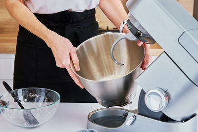 Woman cooking at kitchen and using kitchen machine