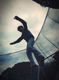 Low angle view of child jumping against sky during sunset