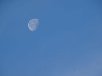 Low angle view of moon against clear blue sky