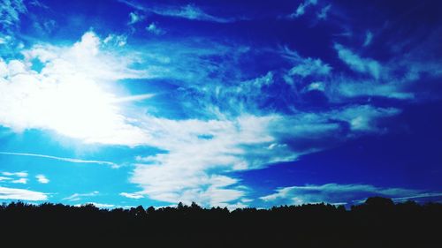 Low angle view of silhouette landscape against blue sky