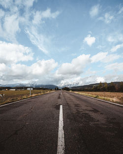 Surface level of empty road against cloudy sky