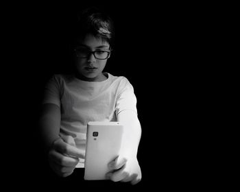 Portrait of young woman against black background