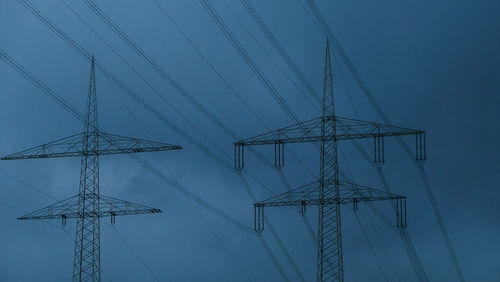 Low angle view of electricity pylon against sky during dusk
