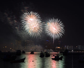 Firework display in city against sky at night