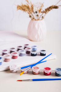 Brushes, multi-colored acrylic paints and canvas for painting by numbers vertical view