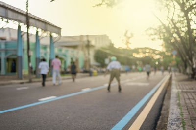 Rear view of people walking on road in city