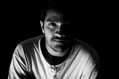 Portrait of young man against black background