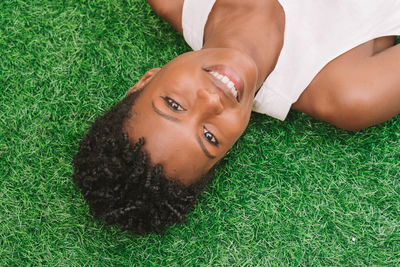 Portrait of young woman lying on grassy field