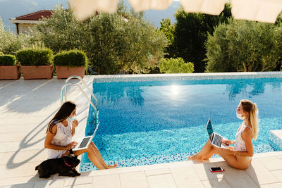 Rear view of woman sitting by swimming pool