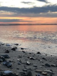 Surface level of beach against sky during sunset