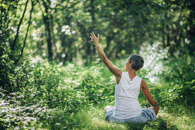 Full length of man sitting by plants in forest