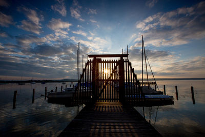 Pier on sea against sky during sunset