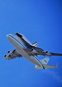 Low angle view of airplane flying against clear blue sky