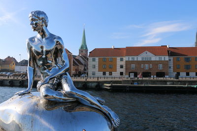 Statue by water against sky