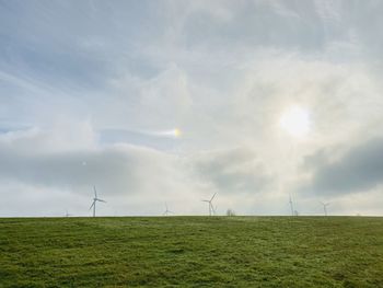 Wind turbines on field against sky