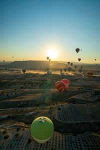 Hot air balloons flying over landscape against sky during sunset