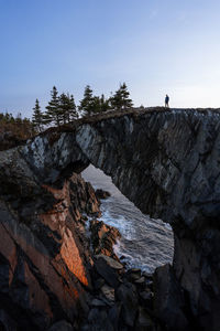 Man hiking at berry head arch at sunrise, along the east coast trail of newfoundland, canada