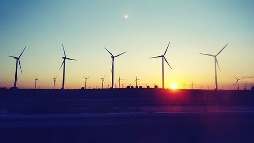 Silhouette windmills against sky during sunset