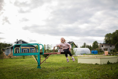 Full length of girl sitting against sky