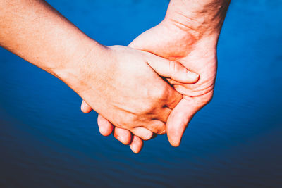 Cropped hand of man and woman against river