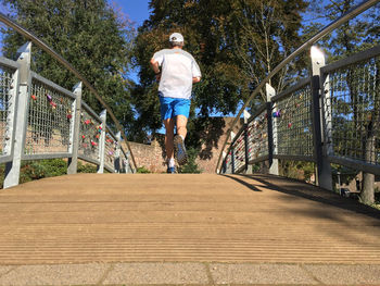 Rear view of man standing on footbridge
