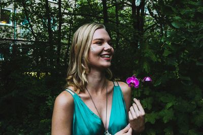 Smiling young woman against trees