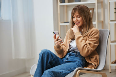 Young woman using mobile phone while sitting at home