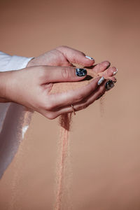 Cropped hands of woman holding sand at desert