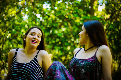 Smiling friends talking while sitting at park