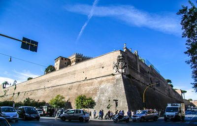 Cars on street in city against blue sky