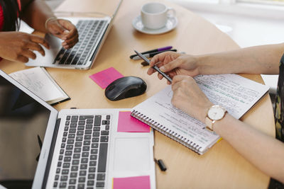 Midsection of woman using smart phone on table