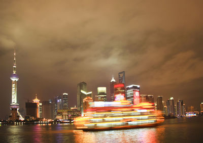 Illuminated modern buildings in city against sky at night