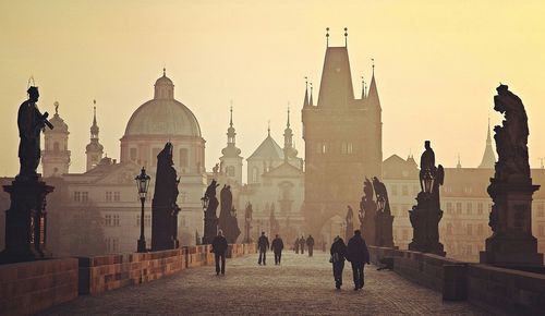 People on charles bridge against buildings against clear sky