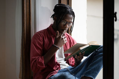 Focused african guy college student wearing eyeglasses learning foreign language by reading books