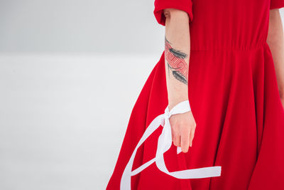 Midsection of woman standing against red background